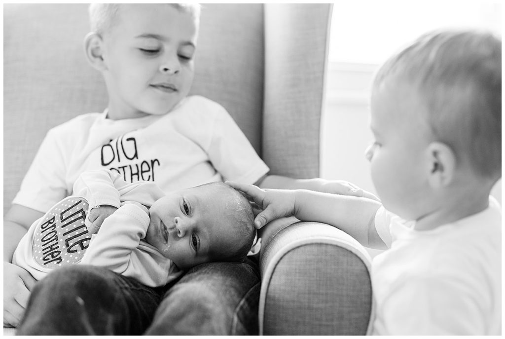 Proud big brothers help comfort their newborn baby brother in this Knoxville family portrait session at home. Photo by Holly Michon Photography