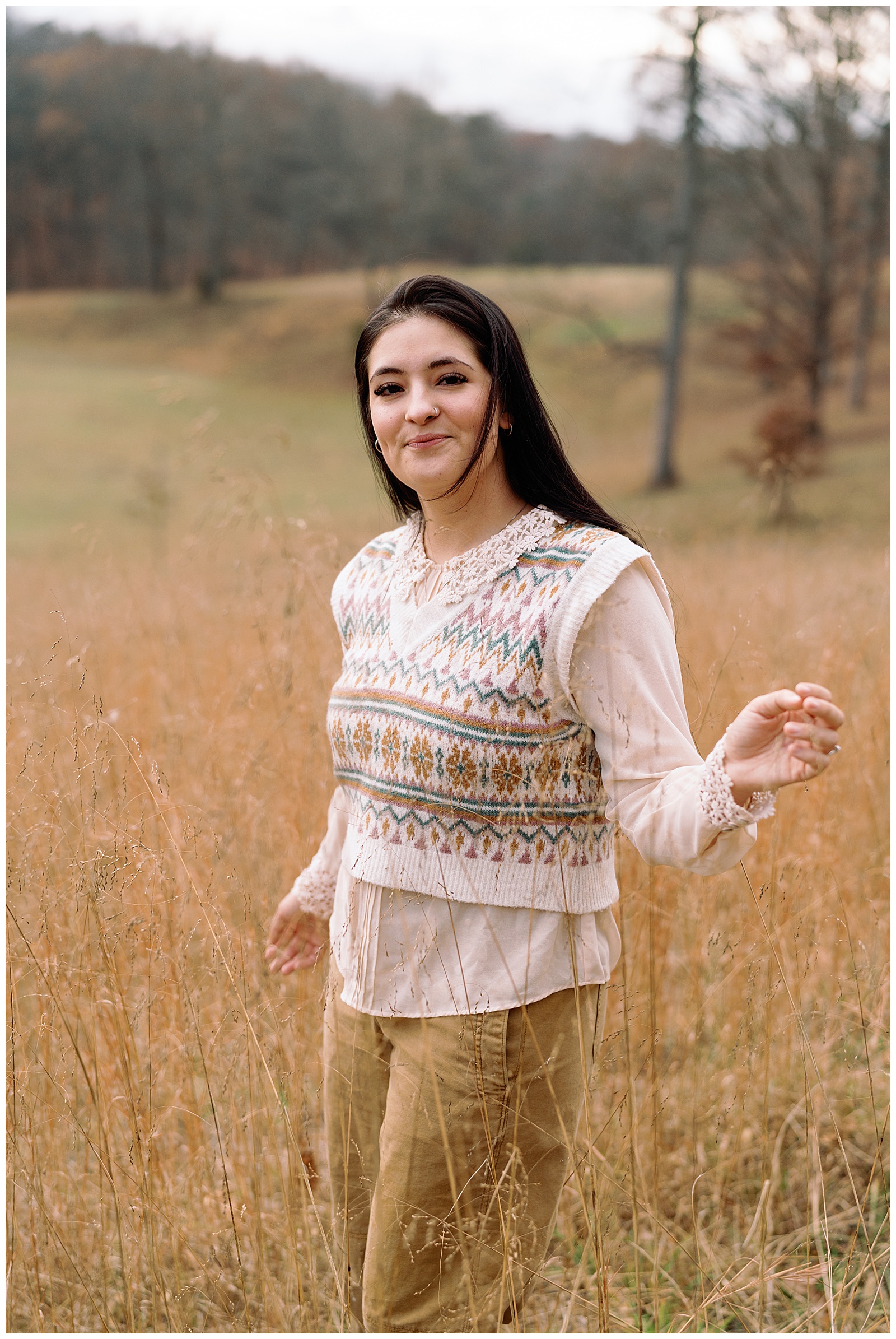 Beautiful woman in a meadow in the winter wearing a sweater vest and blouse