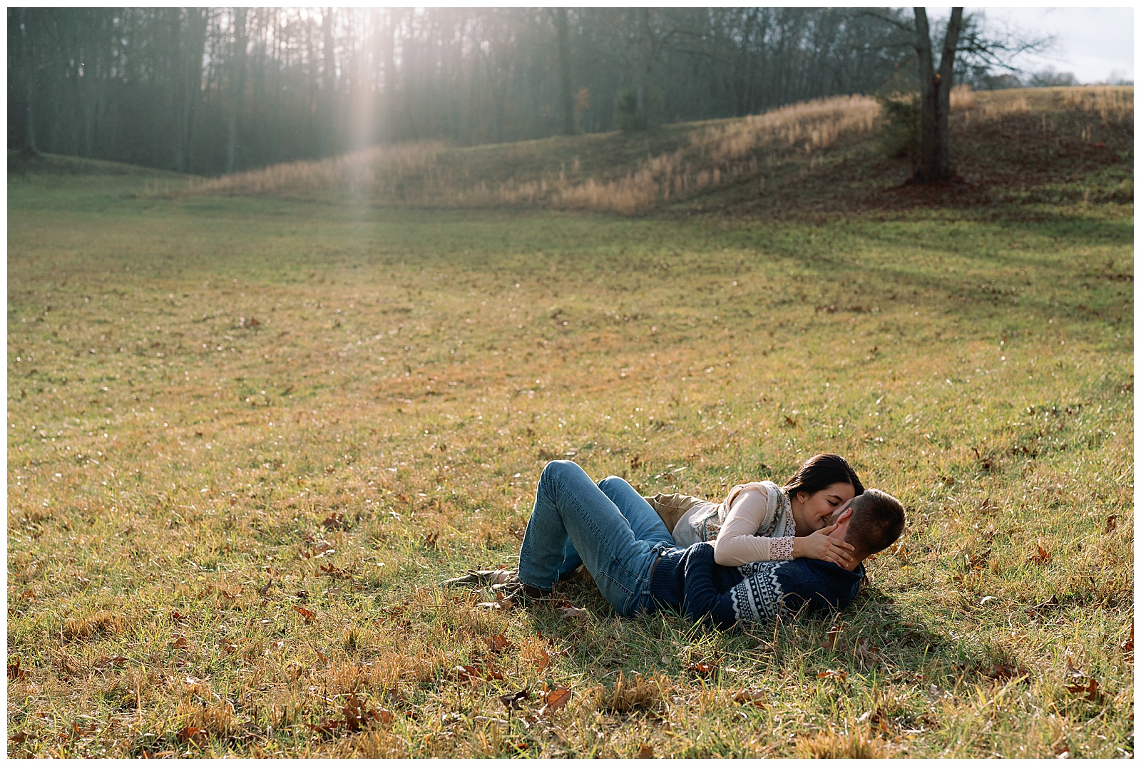 Engaged man and woman lying down and snuggling in a meadow at sunset winter engagement session