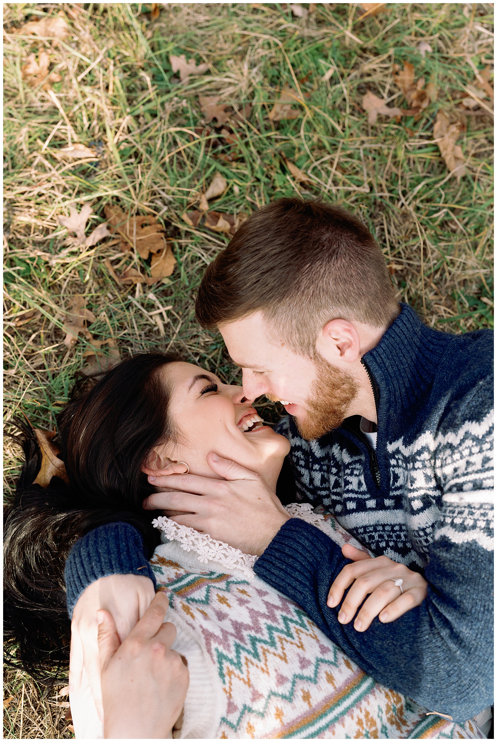 Engaged man and woman lying down and snuggling in a meadow at sunset winter engagement session