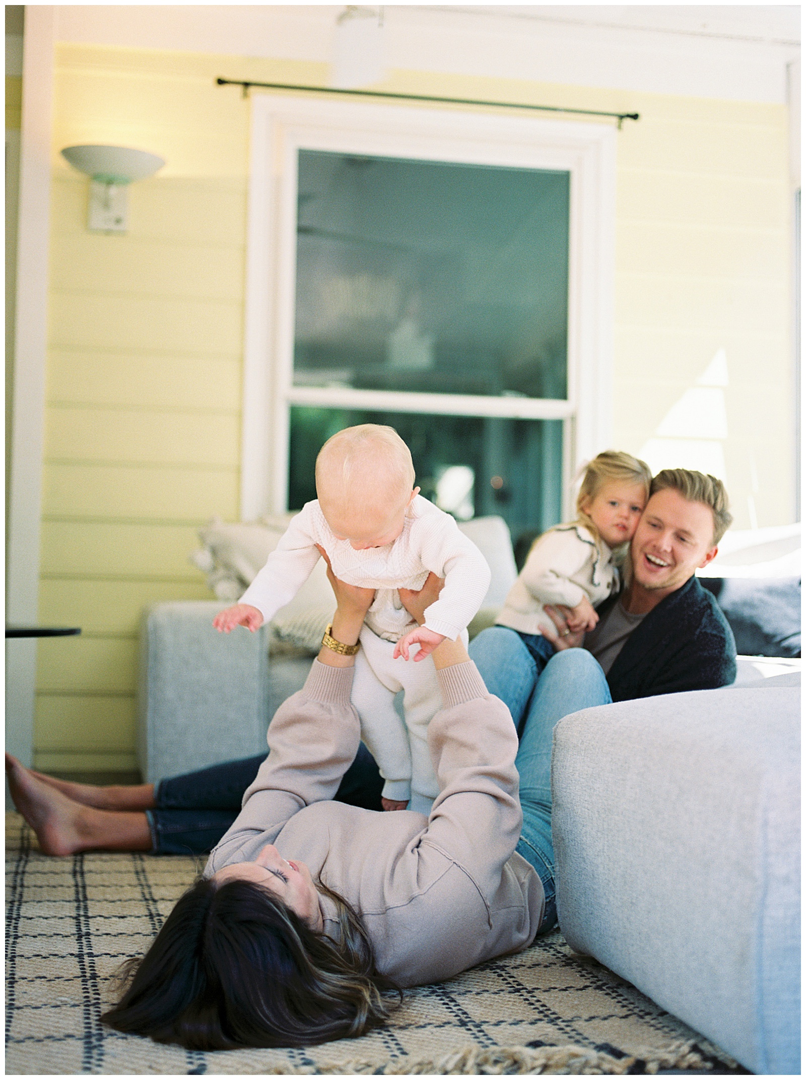 Mom and dad play with their kids for candid photos in their home during their family session by Holly Michon Photography