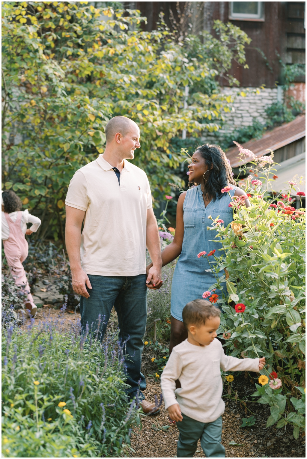 Dad, mom and their children play amongst flowers at Knoxville Botanical Gardens outside for their lifestyle family photo session.