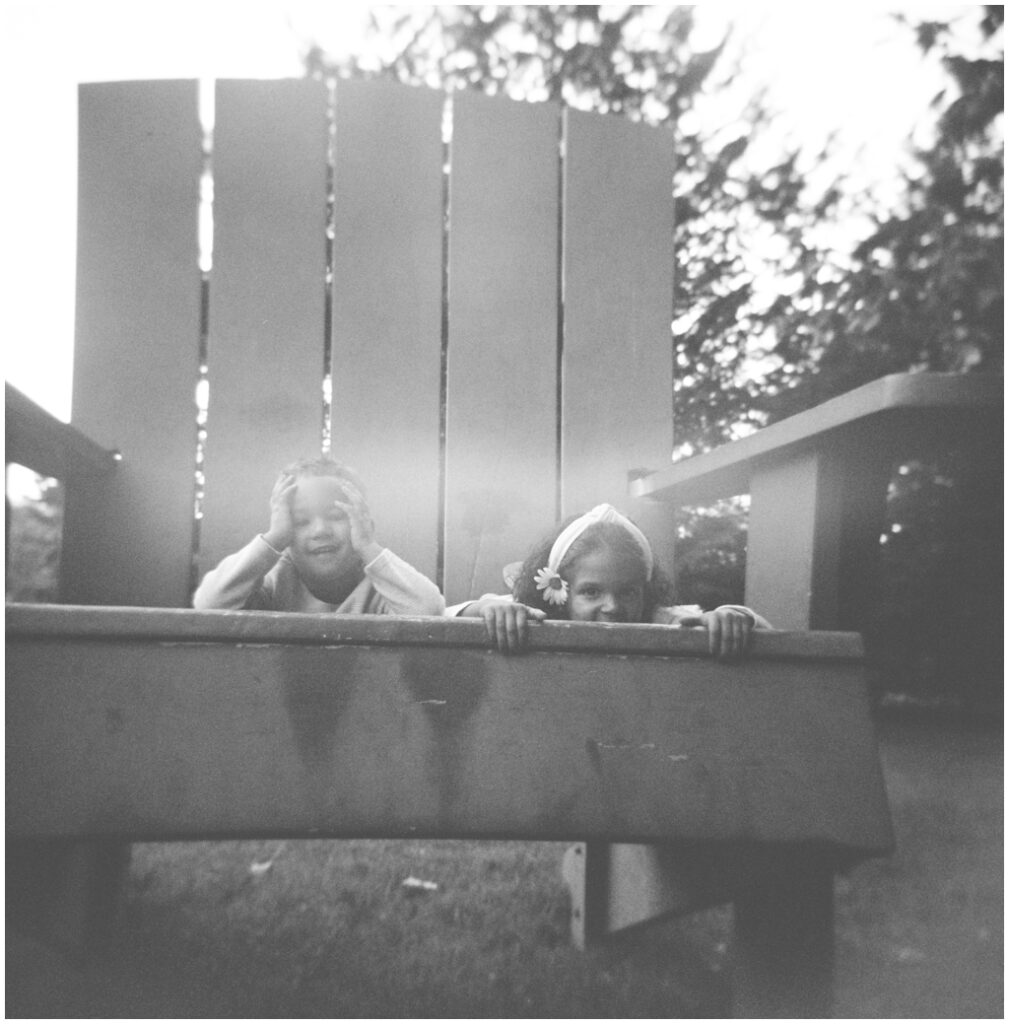 black and white Holga film image of adorable boy and girl on a large yard chair