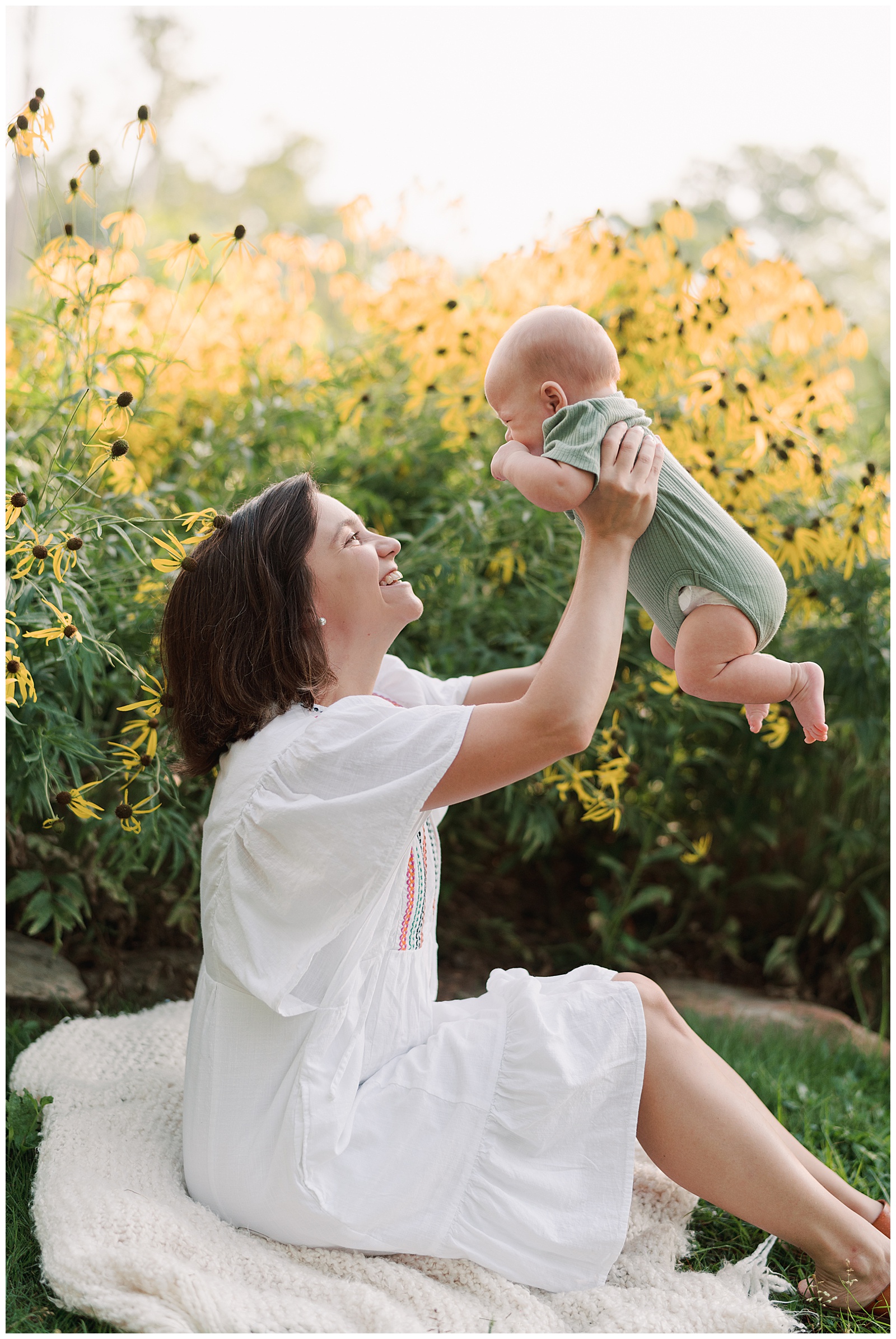 Mom holds son above head in beautiful bright image at UT Gardens in Knoxville, TN.