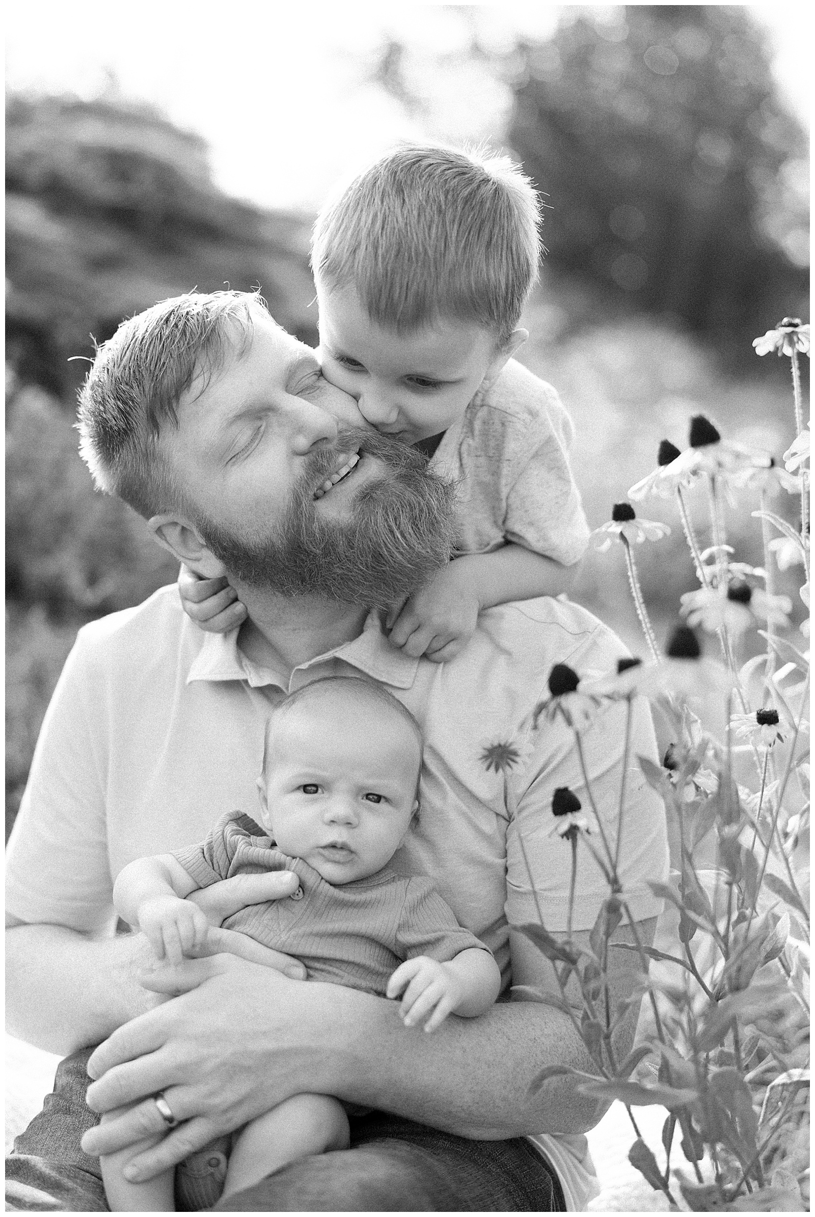 Dad snuggles with sons in black and white image at UT gardens in Knoxville, TN.