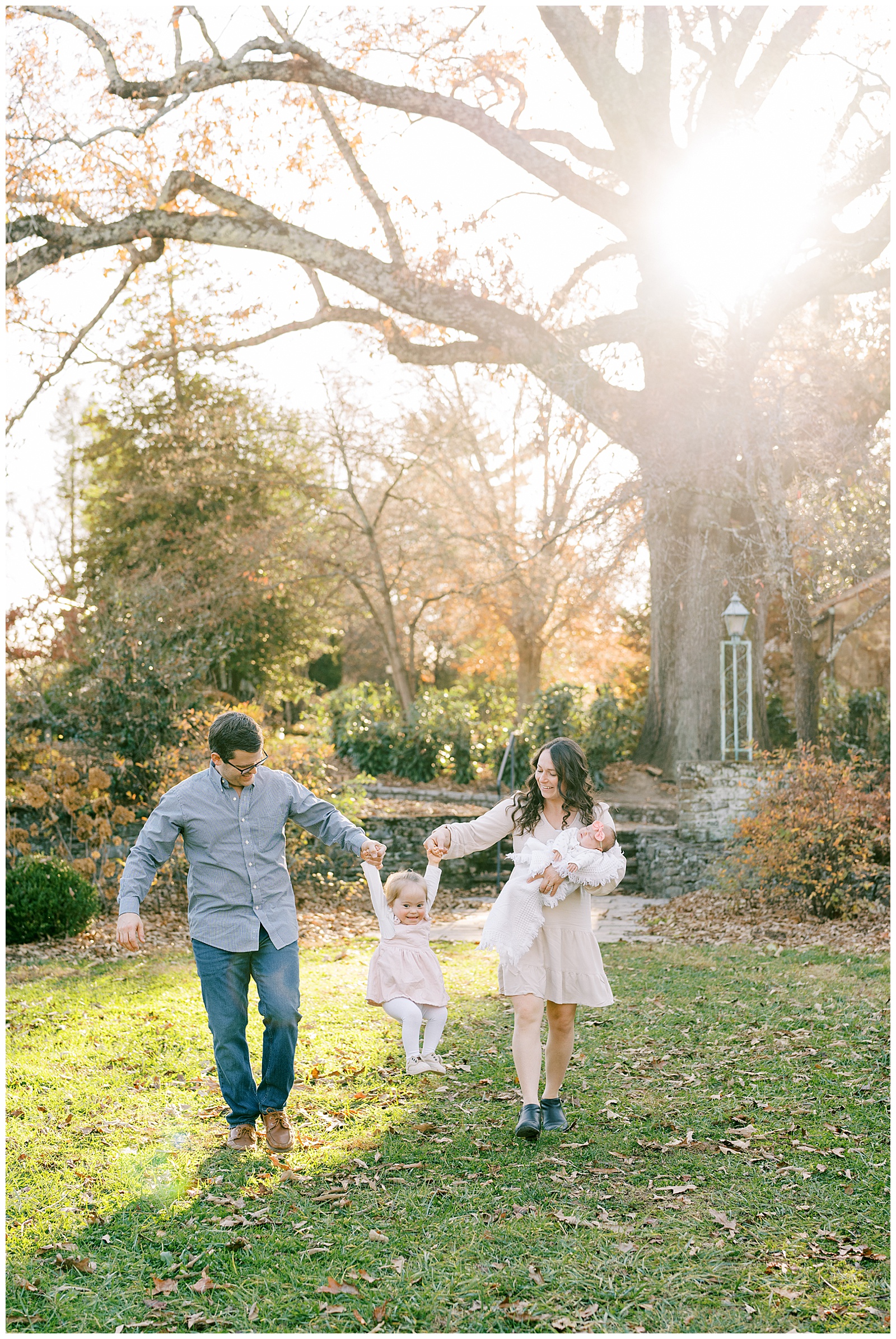 Knoxville family of four swings daughter in vibrant autumn gardens.