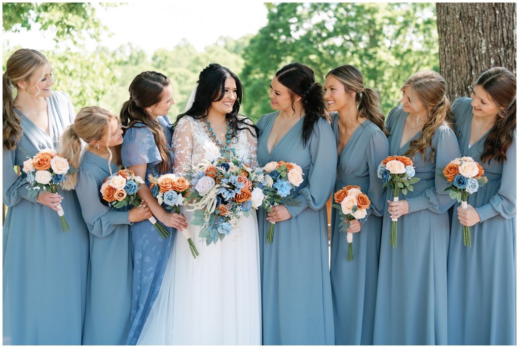 Bride and bridesmaids smile at each other in colorful image of Knoxville spring wedding.