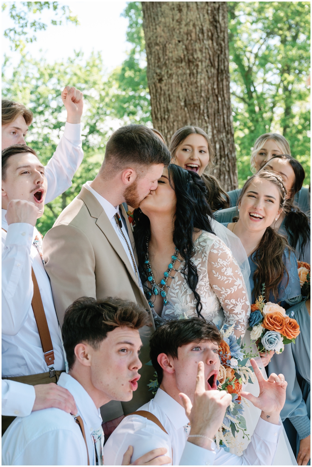 Bride and groom kiss in front of wedding party celebrating in Knoxville spring wedding.