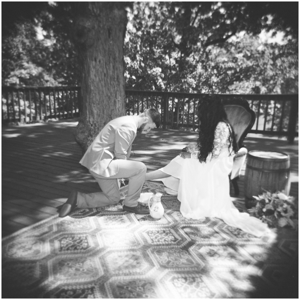 Groom washes brides feet in black and white film photo of Knoxville wedding. 