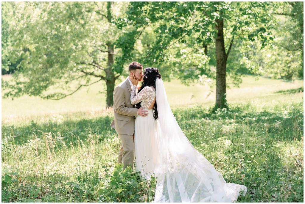 Bride and groom kiss in sunny meadow in East Tennessee.