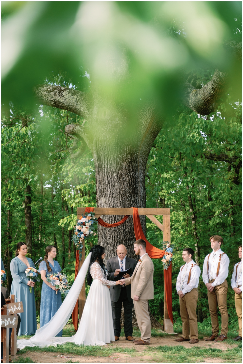 Centered image of bride and groom at altar surrounded by the wedding party.