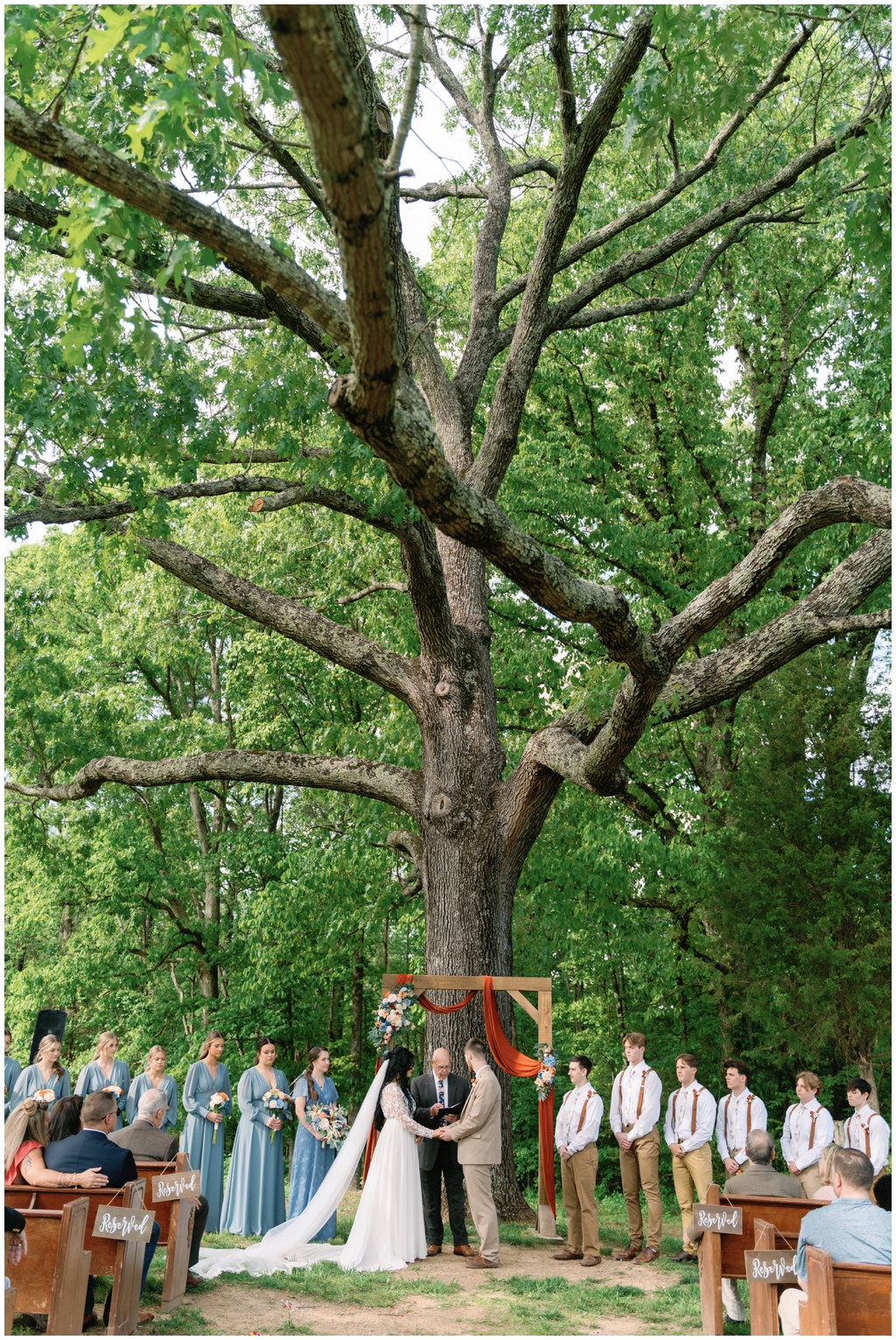 Centered image of bride and groom at altar surrounded by the wedding party.