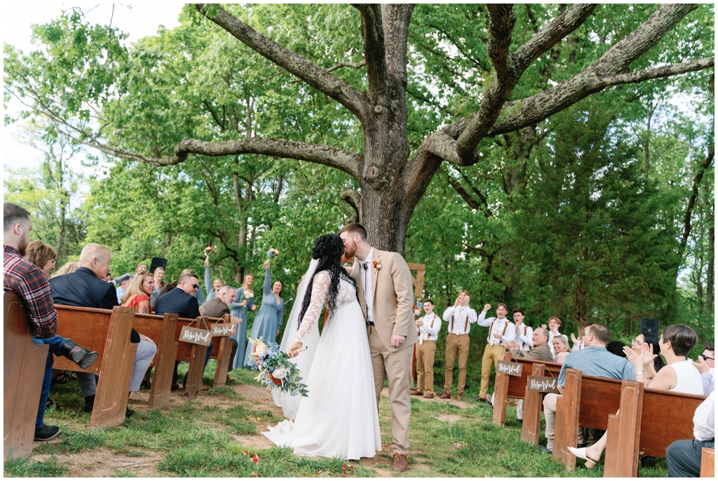 Bride and groom kiss while exiting the wedding ceremony at Knoxville spring wedding.