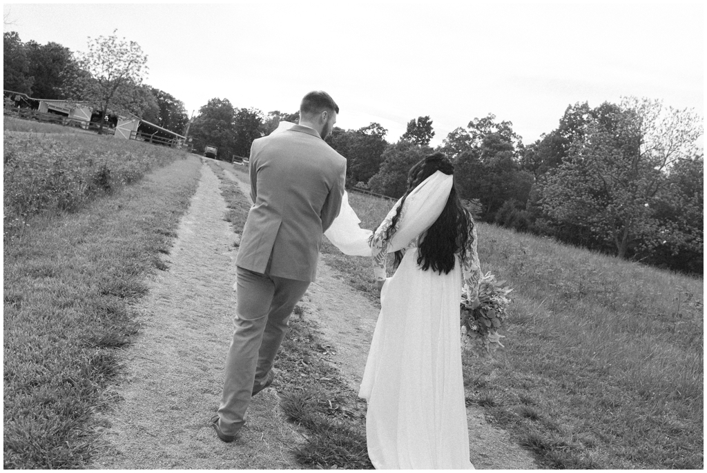 Bride and groom walk to wedding reception in black and white image.