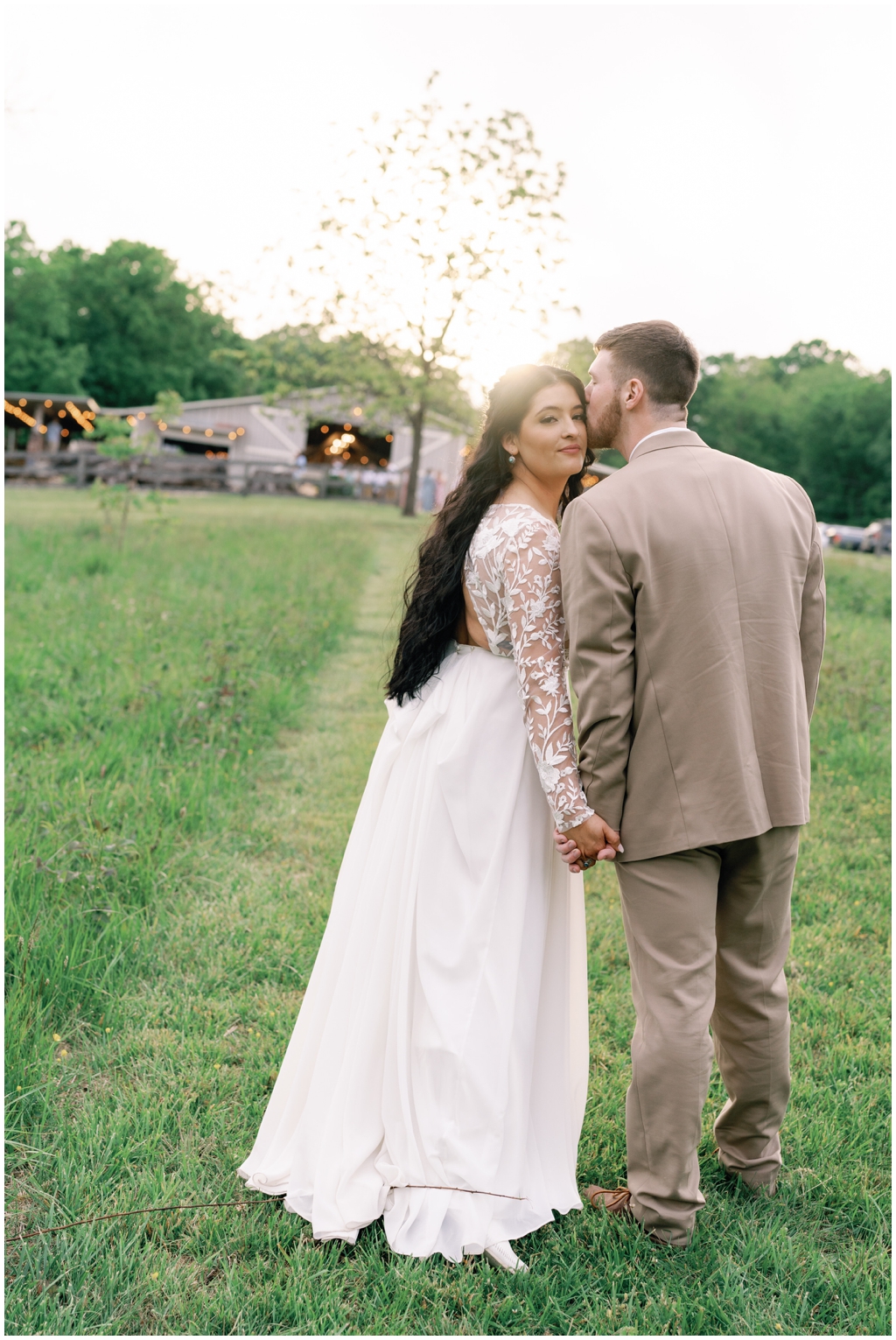 Bride looks over shoulder while groom kisses her cheek in bright Knoxville spring.