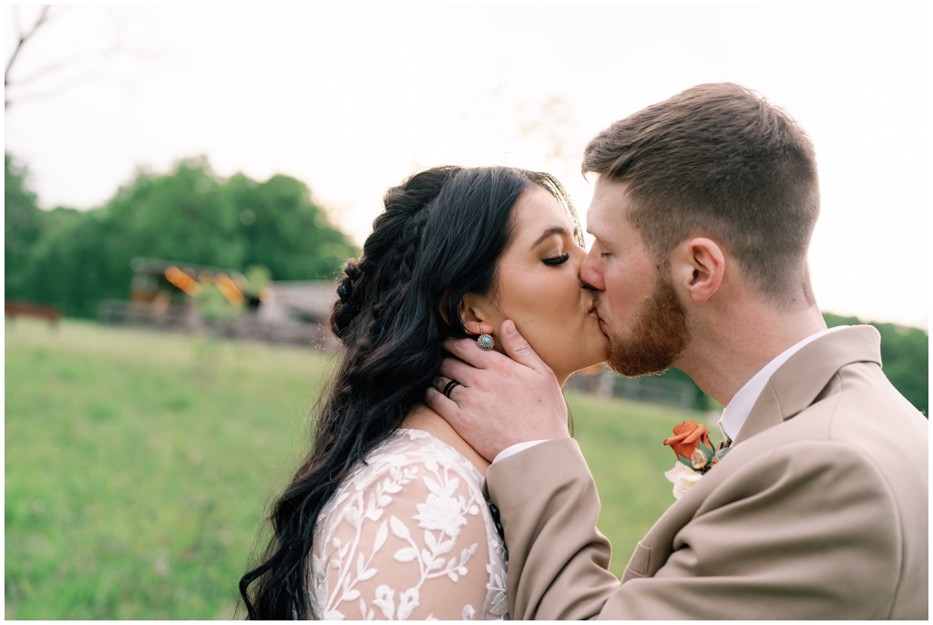 Bride and groom kiss in field during sentimental Knoxville, TN wedding.