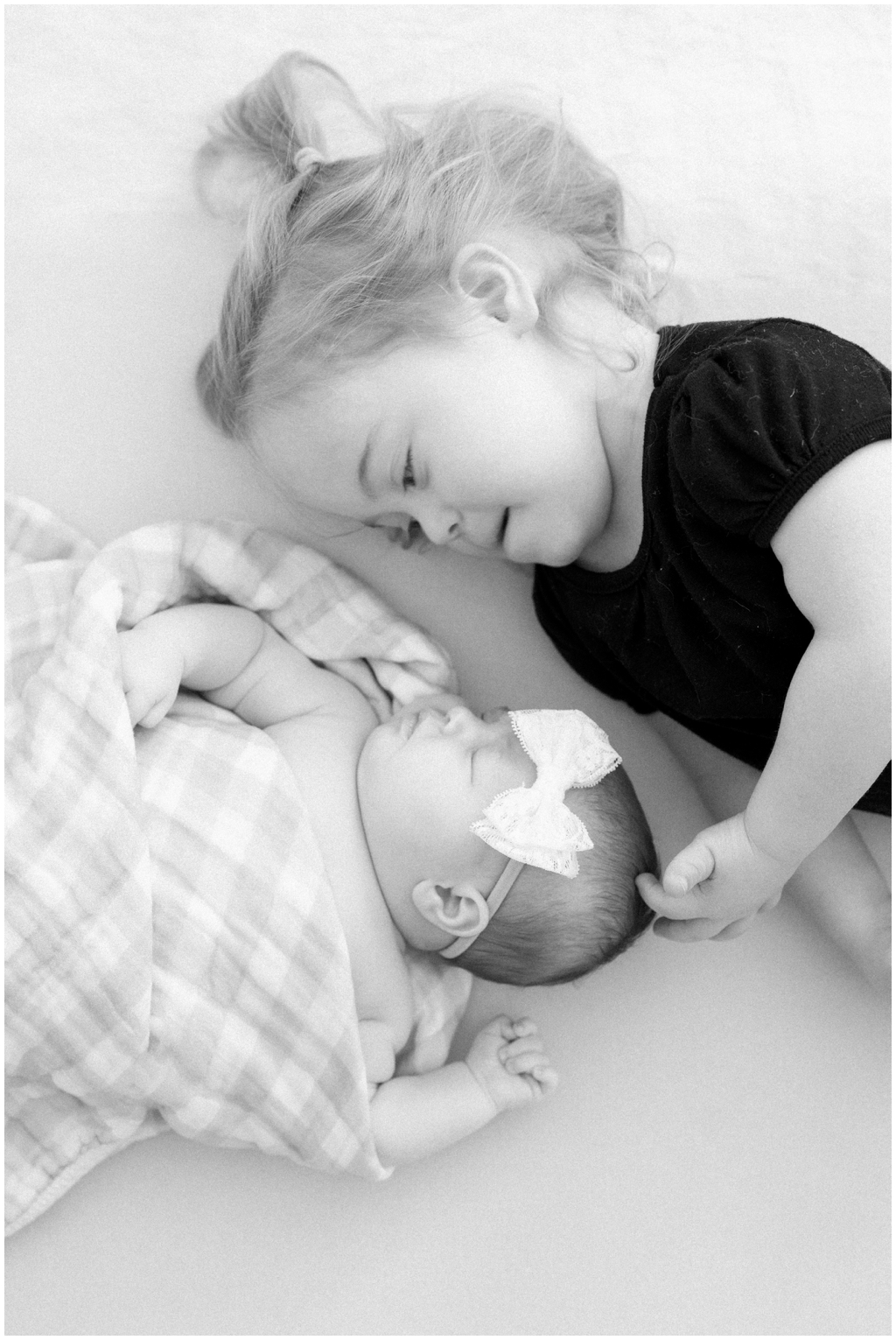 Black and white image of snuggly sister duo during newborn session in Knoxville, TN.