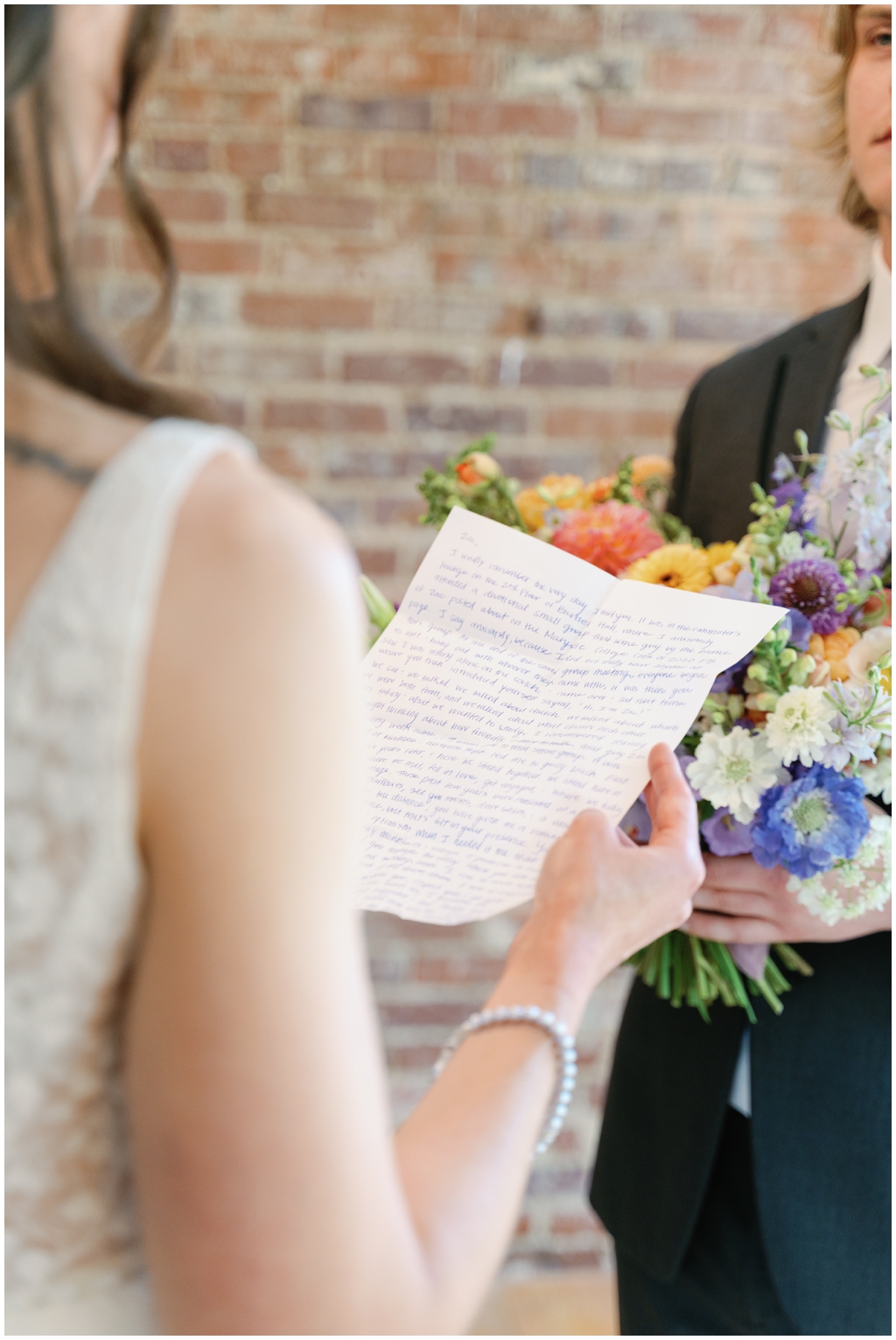 Detail image of brides vows with a bright and colorful floral arrangement in the background.