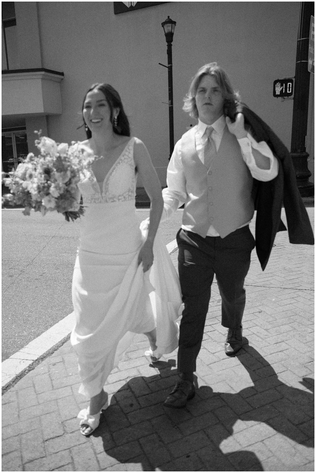 Black and white film image of bride and groom walking through downtown Maryville.