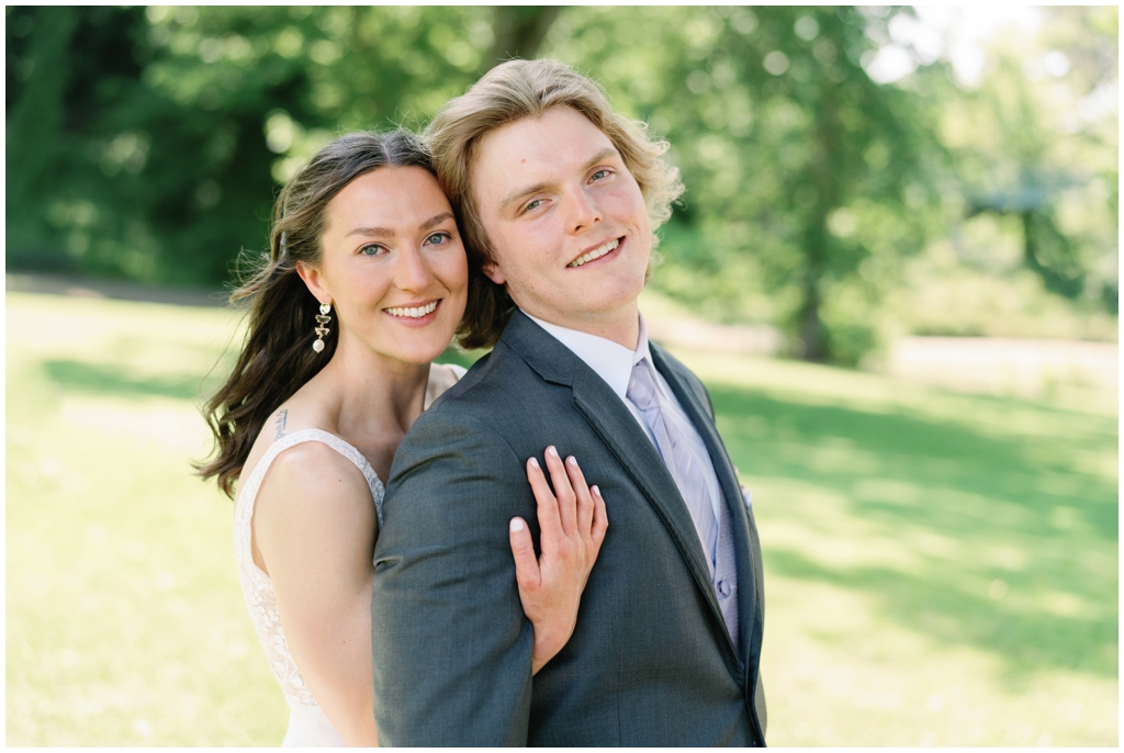 Bride hugs groom from behind in Maryville classy summer wedding.