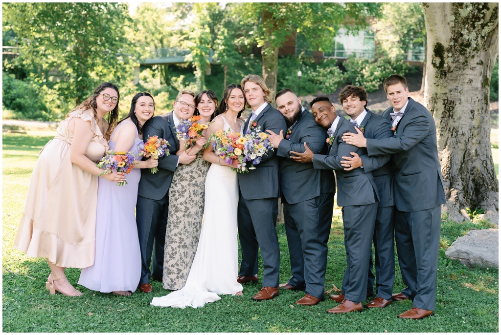 Wedding party sweetly poses together in park for classy and romantic summer Maryville wedding.