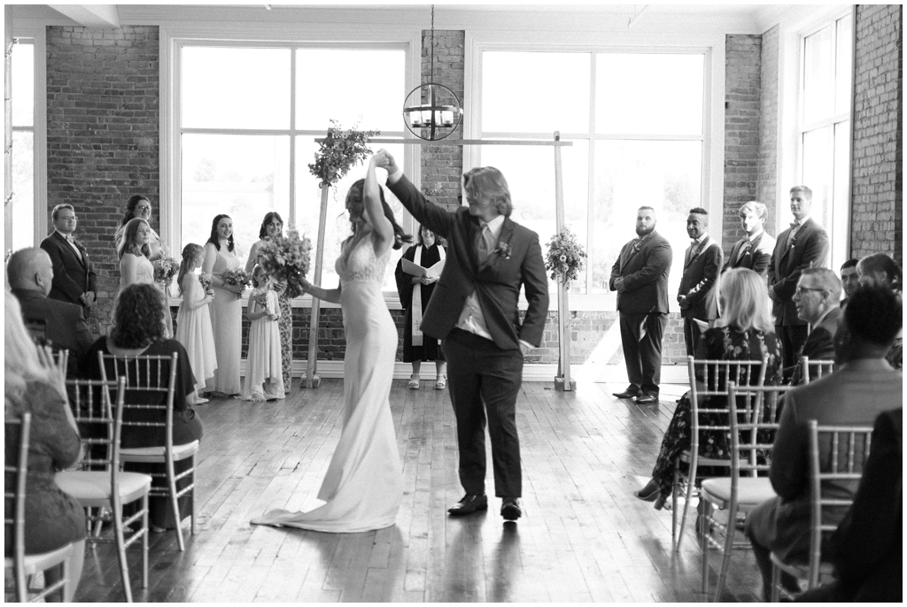 Black and white image of groom twirling bride after ceremony during Maryville wedding.