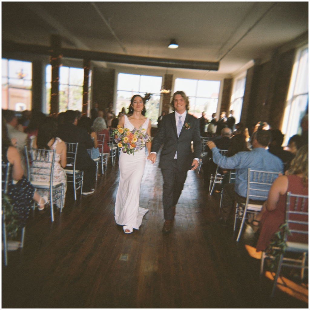 In motion film photo of bride and groom walking down aisle after ceremony in Maryville, TN.