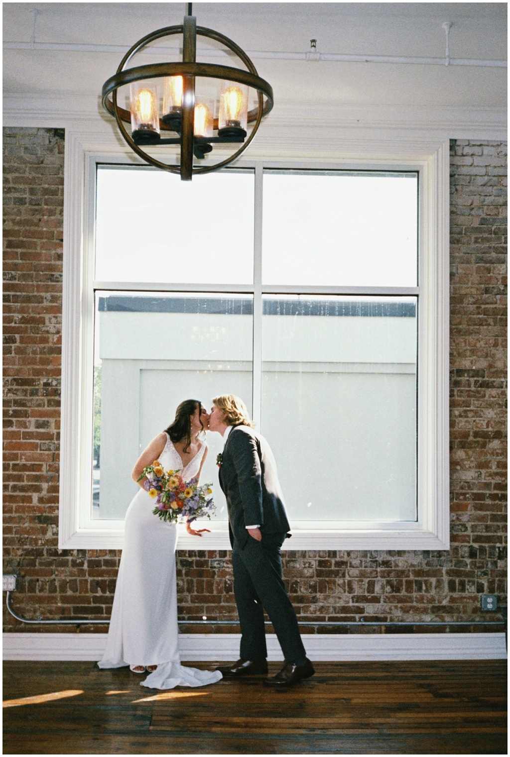 Bride and groom kiss in front of window at Skyview venue in Maryville, TN.