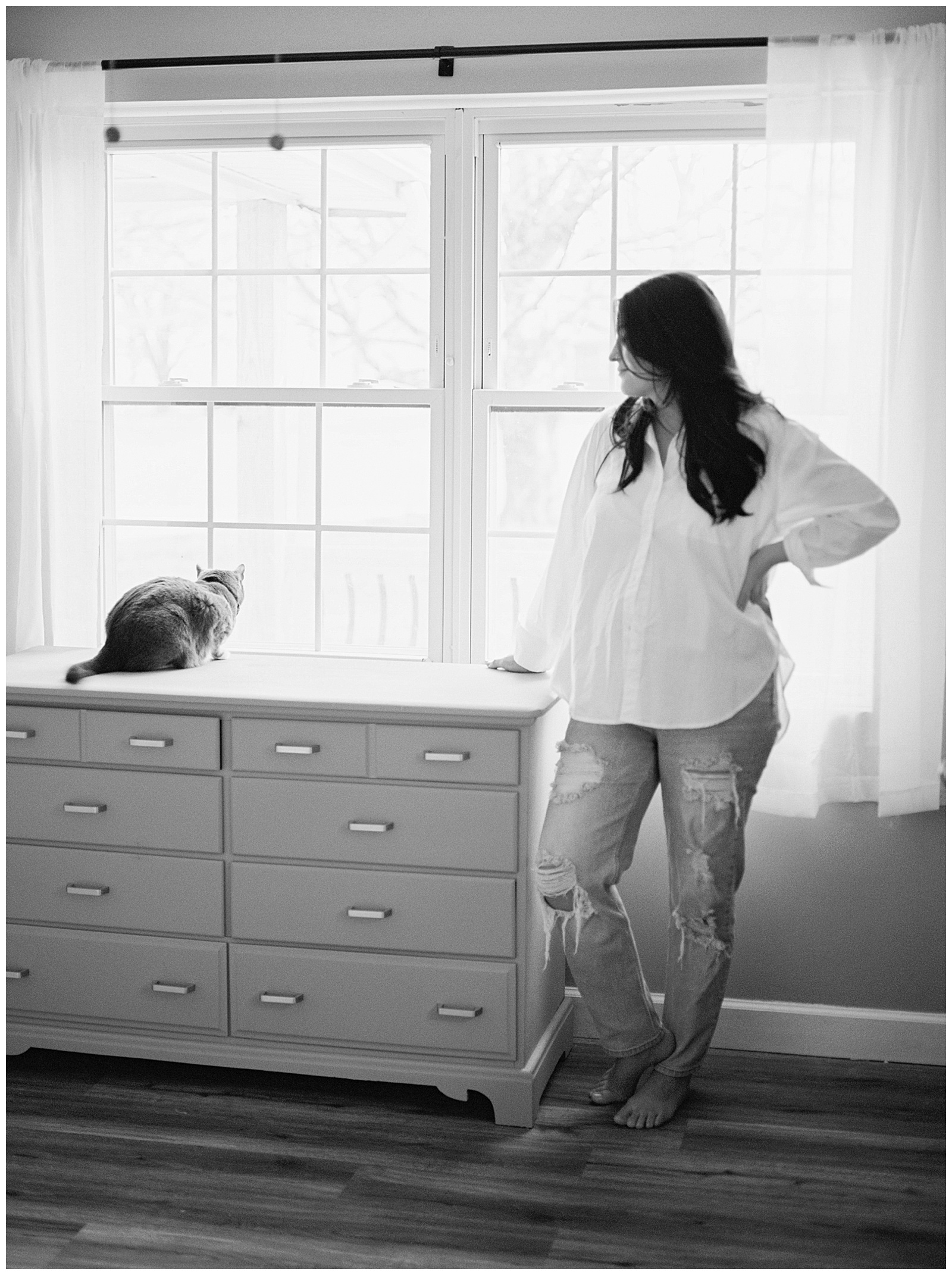 Black and white image of new mom looking lovingly at pet cat.