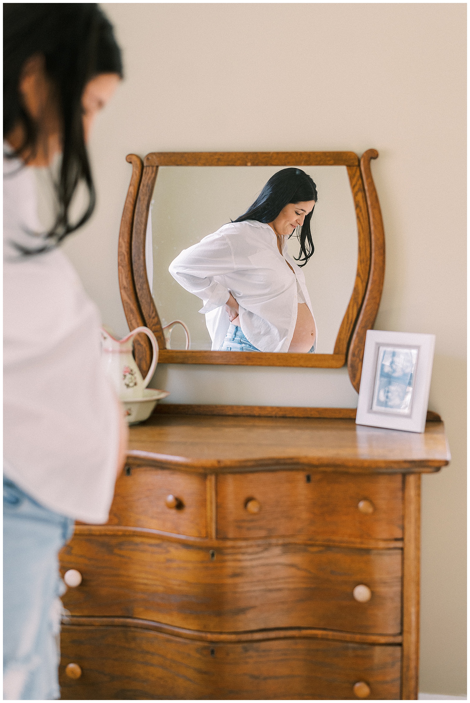 Mom looks down at bump next to mirror in timeless and magical Knoxville maternity session.