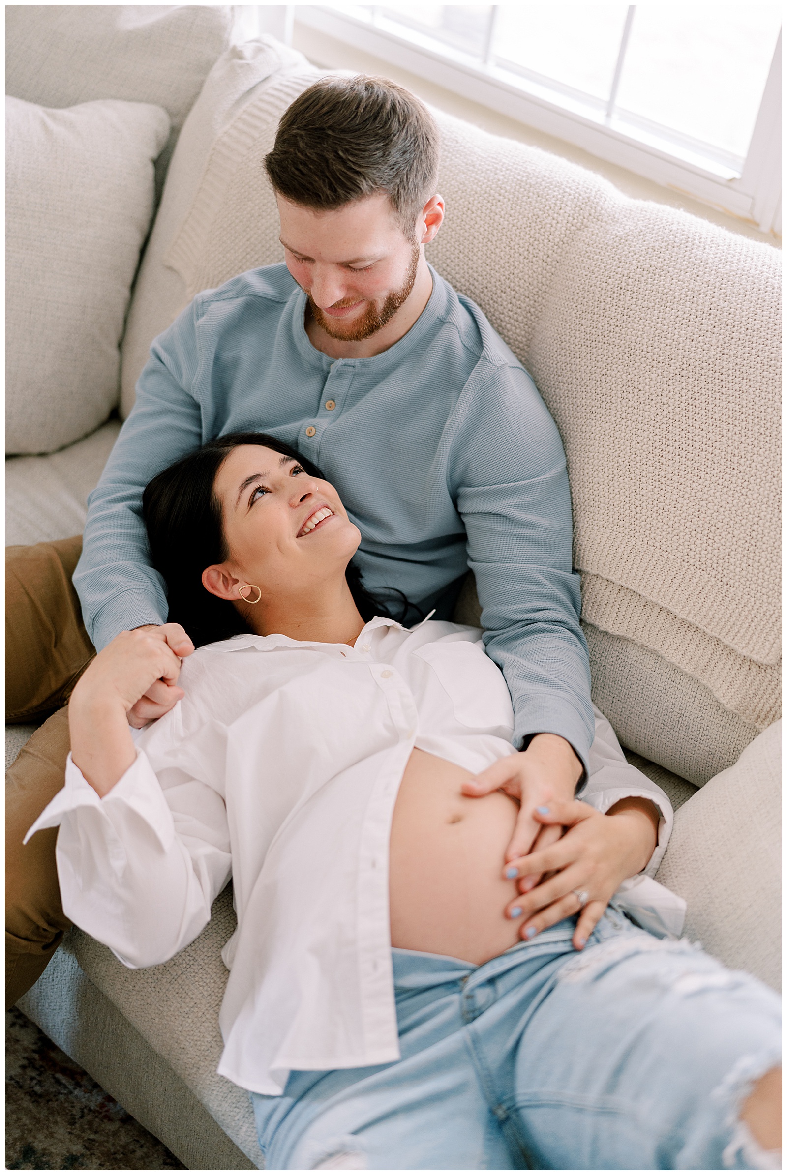 Lucita and Josh snuggle up on couch together in magical in-home knoxville maternity session.