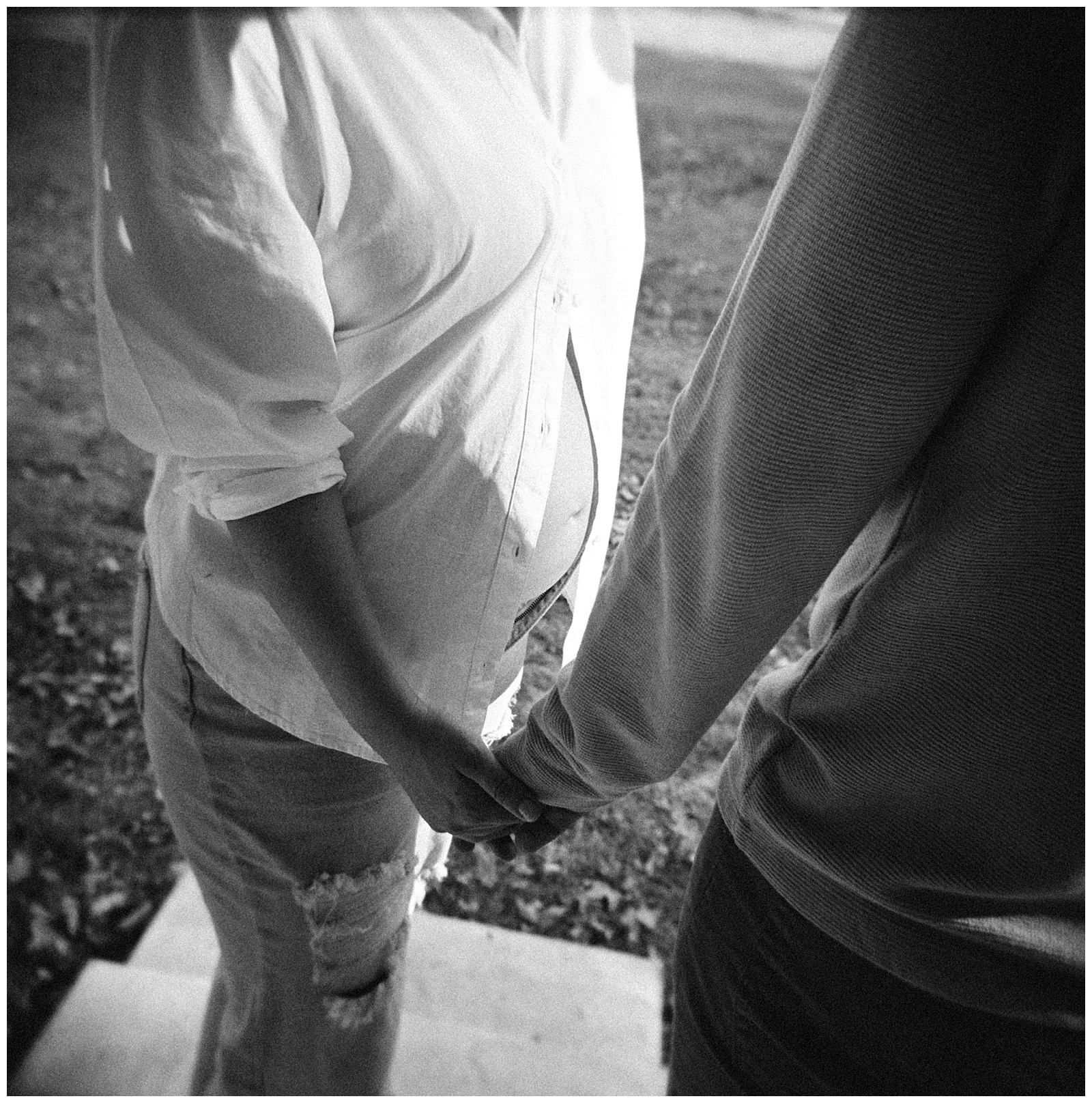 Black-and-white film image of mom and dad holding hands during Knoxville maternity session.