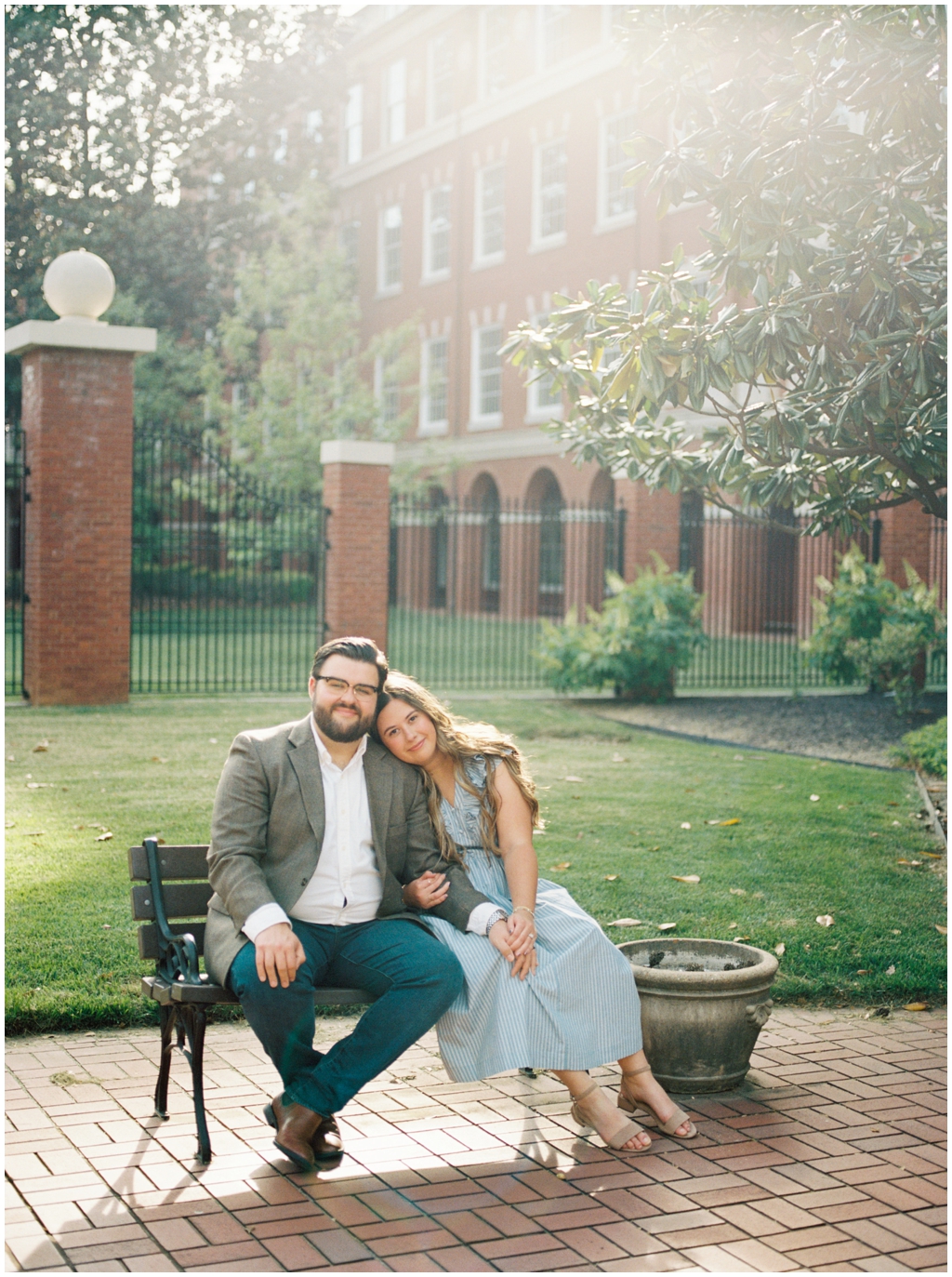 Ashley and Jackson lean on each other while sitting on bench in downtown knoxville during anniversary session