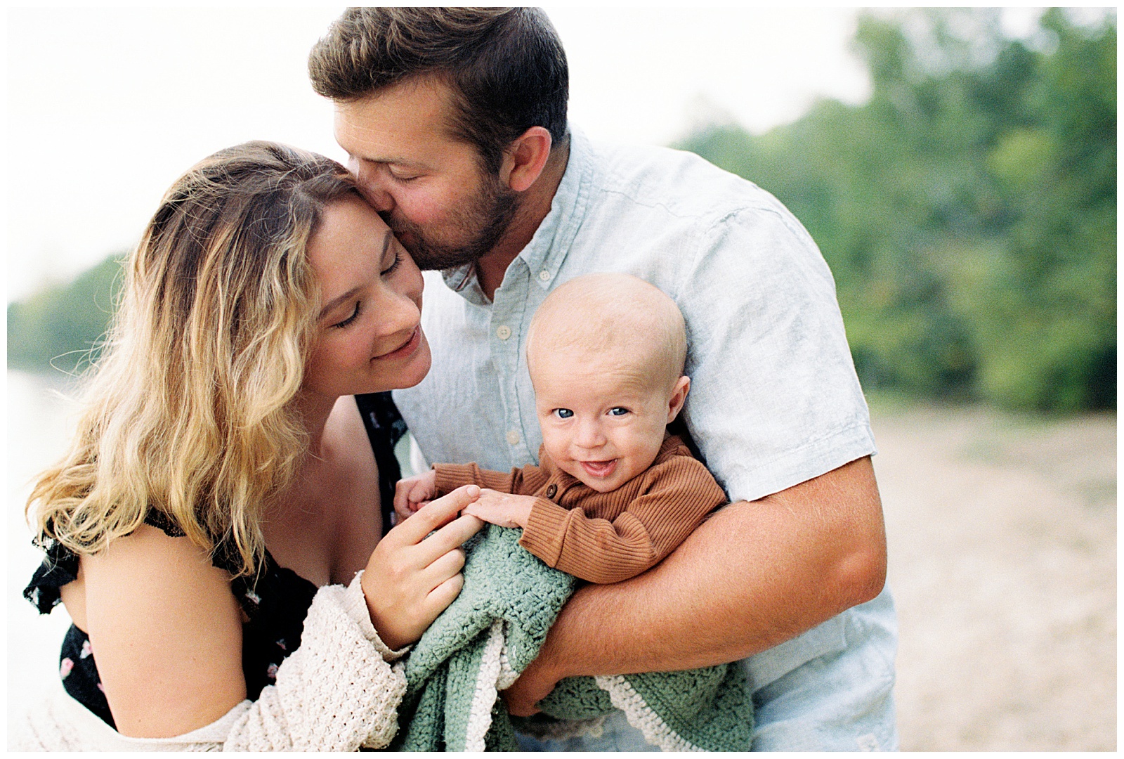 Mom and Dad look at newborn lovingly during relaxed Lake Michigan family session