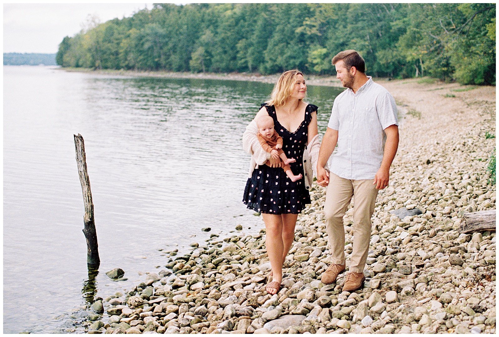 Family of three poses together on the shore of Lake Michigan for family session