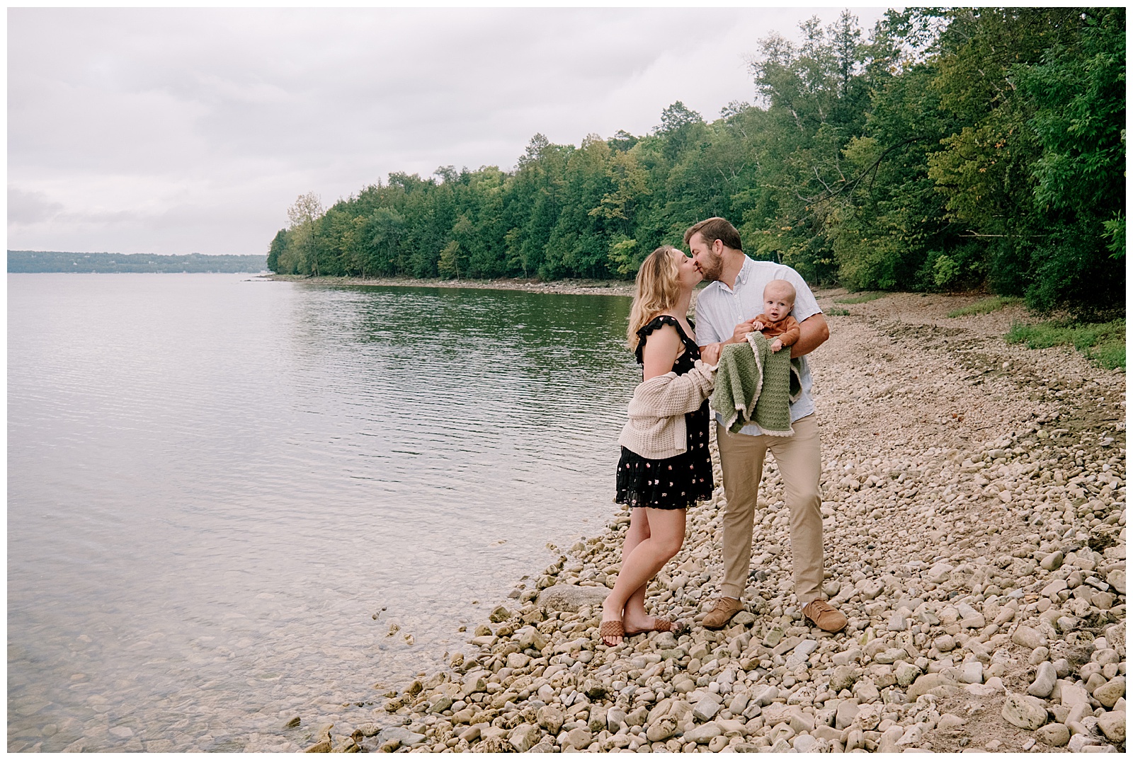 Mom and Dad kiss while holding baby for Lake Michigan relaxed family session