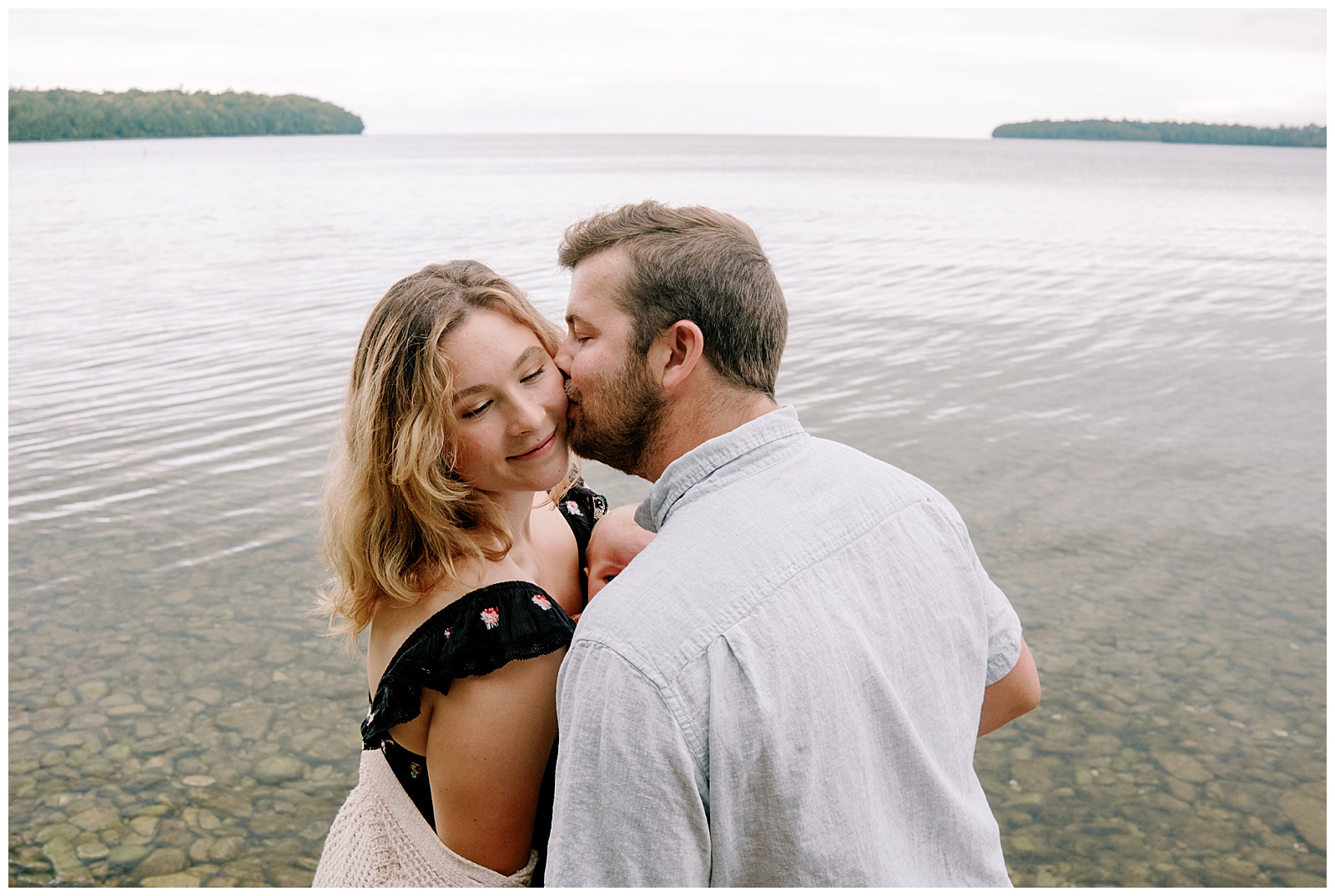 Dad kisses mom on cheek for family session at lake michigan