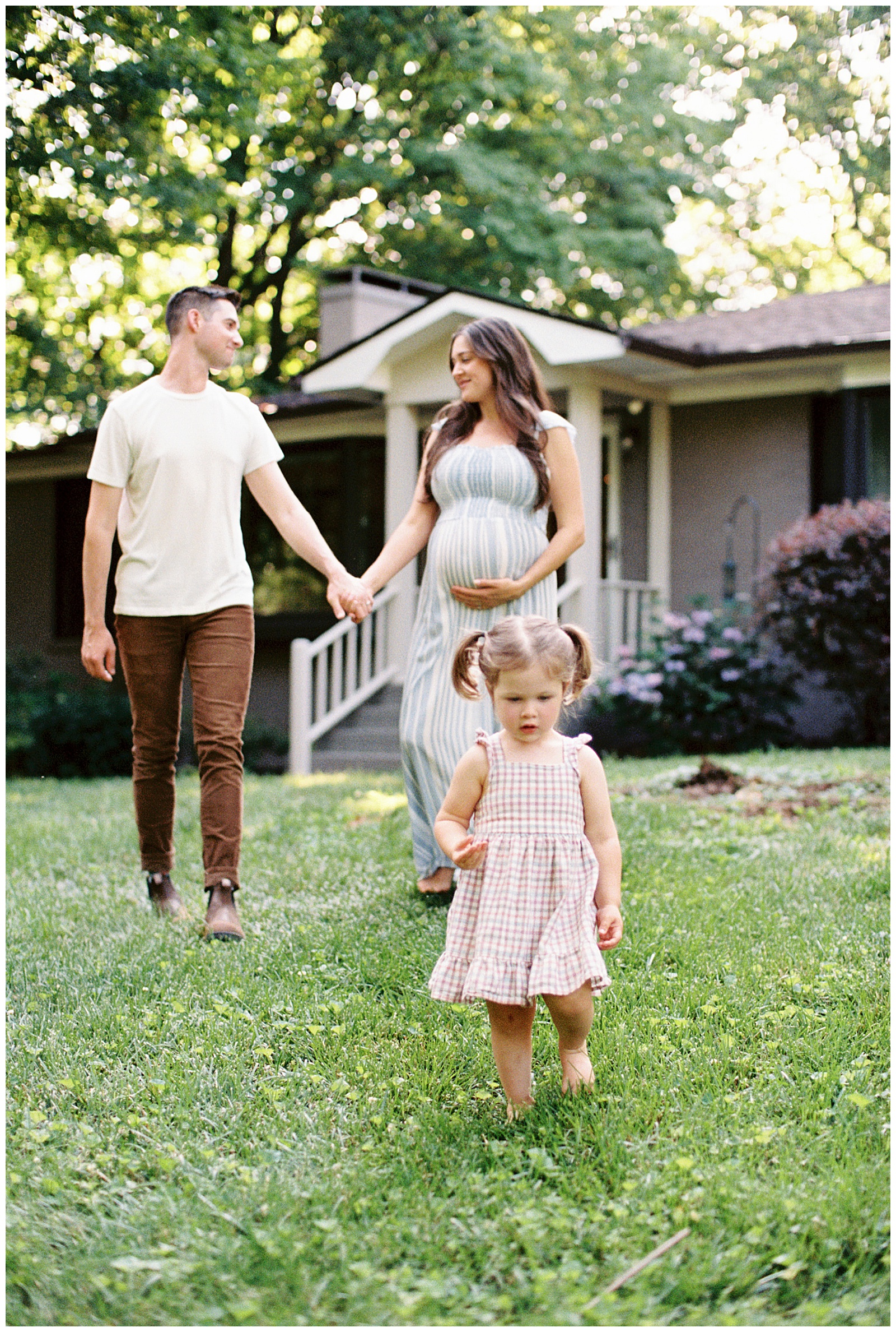 Parents hold hands while they watch their daughter play during summer knoxville maternity session