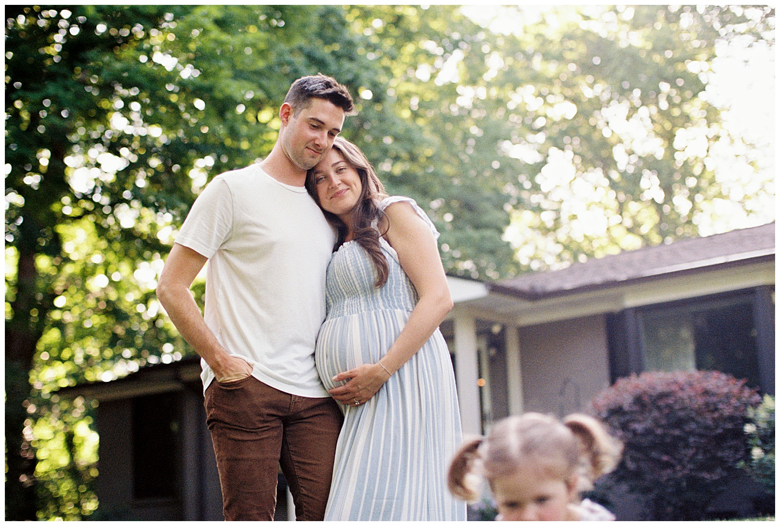 Mom and dad watch daughter play during summer in-home lifestyle session