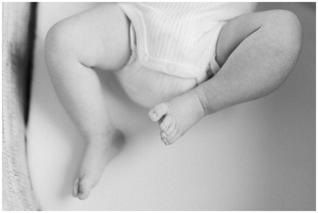 Black and white image of baby newborn feet in a bassinet.